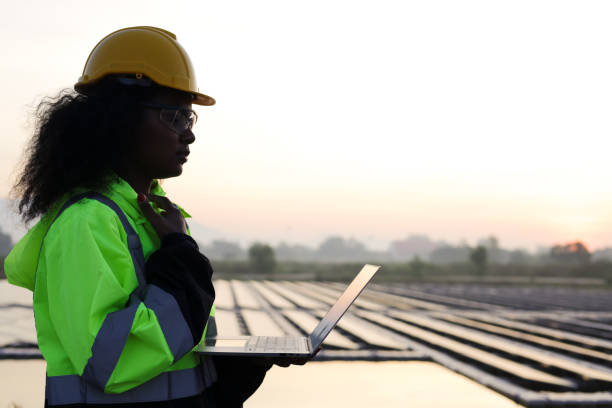 istock Black solar engineer with green safety jacket and laptop working at Solar floating site 1915657084