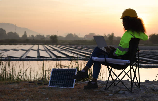 istock Black solar engineer with green safety jacket and laptop working at Solar floating site 1915657085