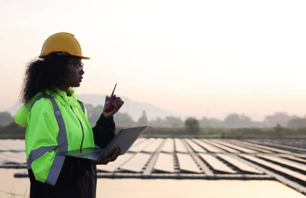 istock Black solar engineer with green safety jacket and laptop working at Solar floating site 1915657090
