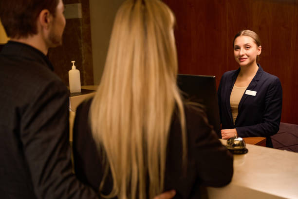 istock Smiling receptionist greeting young couple at reception desk 1915661250