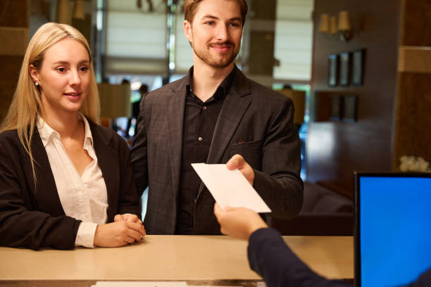 istock Young couple getting paper envelope from receptionist hand 1915661273