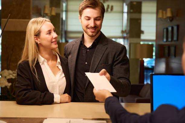 istock Happy young couple getting envelope from hotel administrator 1915661276
