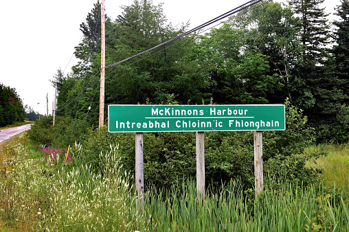 Sign for McKinnons Harbour in Victoria County on the island of Cape Breton in Nova Scotia. Place signs in Gaelic and English are common in Cape Breton due to the high percentage of Scottish Highlanders that settled there