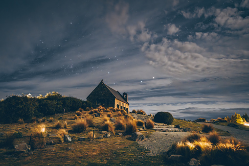 Experience the mesmerizing beauty of New Zealand's Church of the Good Shepherd under a starry night sky. A celestial spectacle awaits.