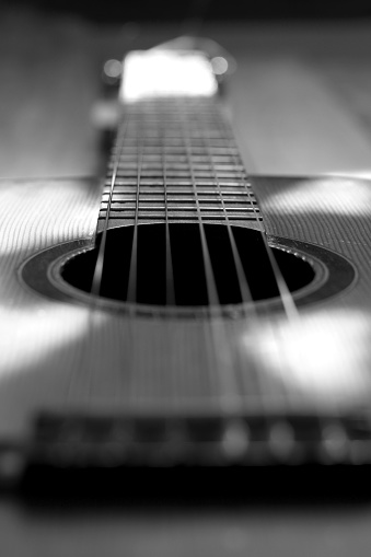close-up of an acoustic guitar, neck, strings, soundboard, black and white photo