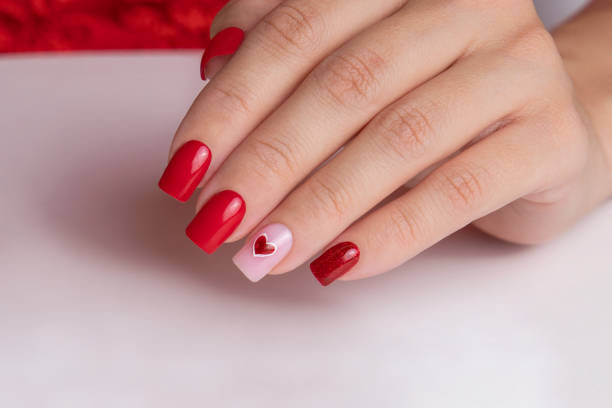 istock Female hand with red manicure nails, heart design 1915714070