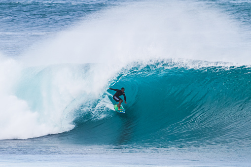 Sea waves, surfers, and white foams roll in at the shore in Huntington Beach, California