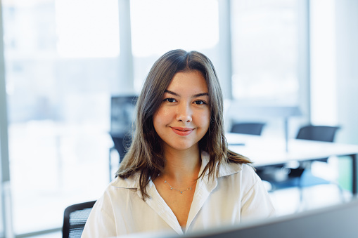 Happy Young Businesswoman at Office Desk: Smiling Portrait.
Capture the vibrant spirit of a young businesswoman in this cheerful stock photo. Seated at her office desk, she smiles and poses from behind her laptop, radiating positivity and confidence. The image conveys a sense of professional contentment and enthusiasm in the workplace. The modern office setting enhances the overall ambiance of productivity and success. Perfect for business-related promotions, corporate publications, and social media content, this photo showcases the joy and fulfillment of a successful work environment.Young businesswoman, Office desk, Laptop, Smiling portrait, Positive attitude, Confidence, Workplace, Modern office, Productivity, Success, Business promotions, Corporate publications, Social media content