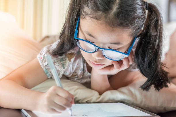 istock School child girl kid using internet online learning on mobile tablet reading looking at digital screen for educational study for Children’s Eye Health and Safety Month and Blue Light Awareness Day 1915858806