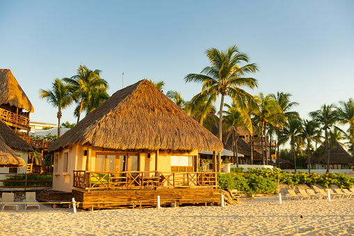 In Playa del Carmen, Mexico a hotel with a thatched roof typical of Quintana Roo is landscaped with palm trees along the beach.