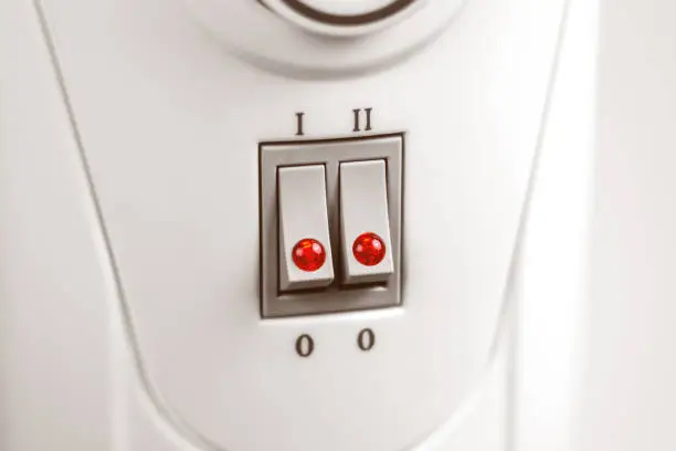 Turned on hot heating radiator with two switches and indicator red lights. Control panel objects close up