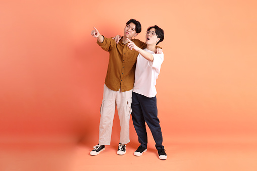 The Adult east 20s two friends with braces standing on the pink or orange background.