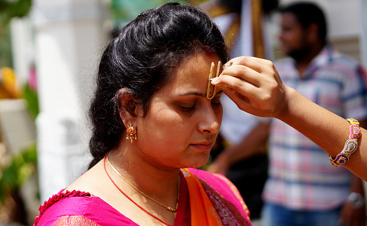 HYDERABAD,INDIA-AUGUST 24,2019: Indian Hindu woman apply Tilak on fore head of a devotee,a religious ritual,on Krisnastami festival celebration in God Krishna temple