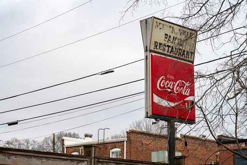 Huntersville, North Carolina, United States - 6 Jan 2024: Explore the charm of a worn Coca-Cola sign at Huntersville Family Restaurant. Vintage allure, nostalgic vibes, and a touch of Americana in the weathered sign.