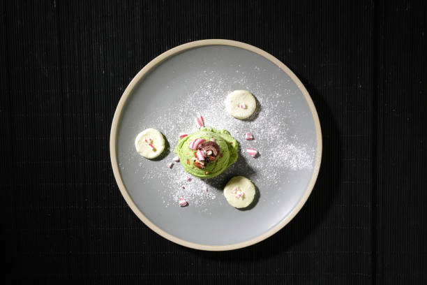 istock On a black background, a plate of attractive matcha ice cream is displayed. Minimalist space with flat top-down perspective. Scene for advertising. 1916096196