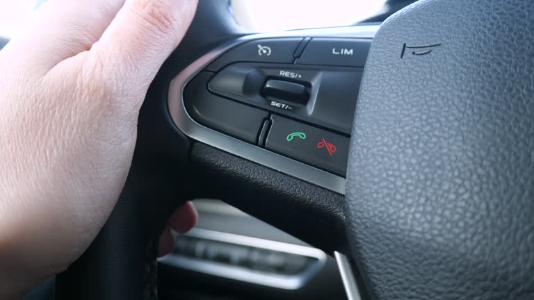 The driver presses the button to pick up the phone on the steering wheel of the car, close up