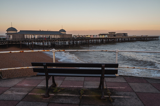 Hastings, East Sussex, England, UK - May 11, 2022: Evening mood on the beach, with a bench overlooking the the pier