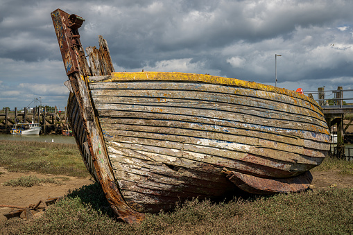 Rye Harbour, East Sussex, England, UK - May 12, 2022: An old shipwreck and some boats on the banks of the river Rother