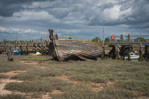 Rye Harbour, East Sussex, England, UK - May 12, 2022: An old shipwreck and some boats on the banks of the river Rother