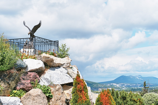 Zlatoust, Russia - June 20, 2023: Bazhov Mountain Park, tourist attraction of Southern Urals. Copper sculpture of Eaglet feeding chick with fish on natural marble pedestal. Author- blacksmith Chirkov