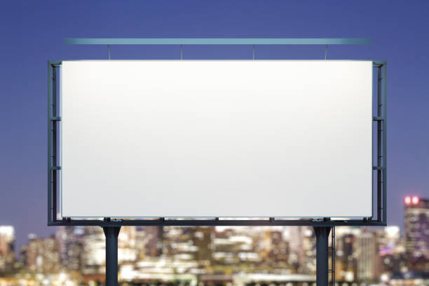 istock Blank white horizontal billboard on city buildings background at night, front view. Mockup, advertising concept 1916314348