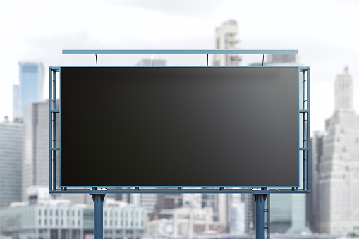 Blank black billboard on city buildings background, front view. Mockup, advertising concept