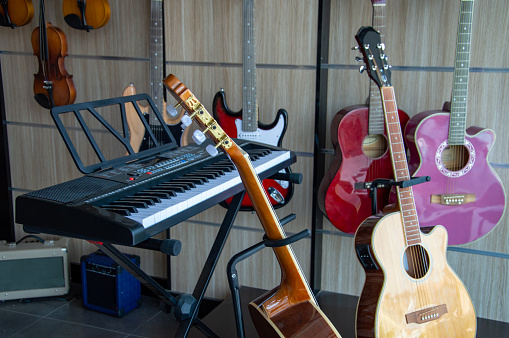 There are acoustic guitars, violins and piano in the window of the music store, but no one is there. Assortment in musical instrument store, professional equipment for musicians and artists