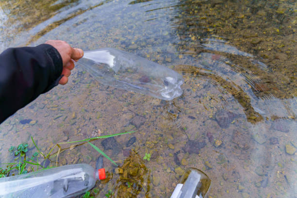 istock man collecting plastic bottles on the shore of a river 1916345923