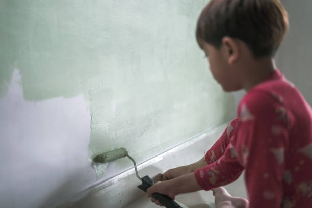 istock Child Boy paints on house wall 1916423013
