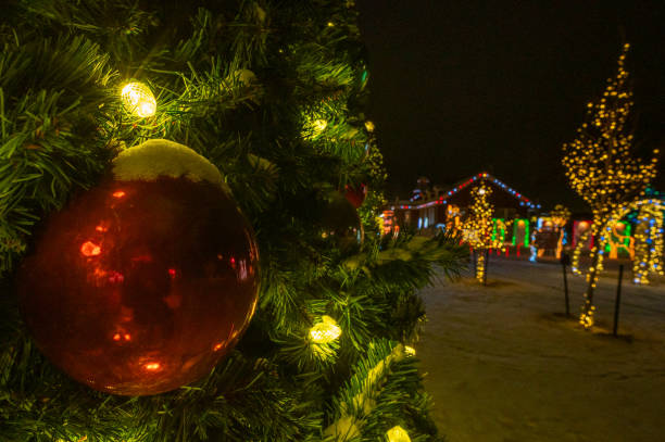 Christmas bauble on Christmas tree with Christmas lights and more lights in the background