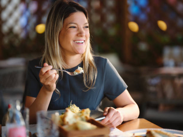 happy businesswoman eating risotto for lunch in a restaurant. - smart casual occupation casual healthy eating стоковые фото и изображения