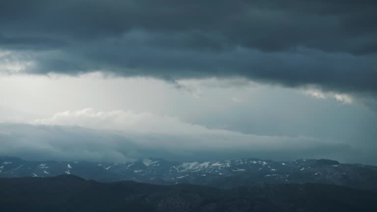 Dense heavy white clouds carried by the strong wind,  roll above the forest-covered coast of the Hardanger fjord.