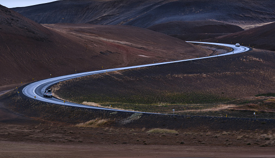 Panoramic view of winding road with cars driving on it in Iceland. Photographed in medium format.