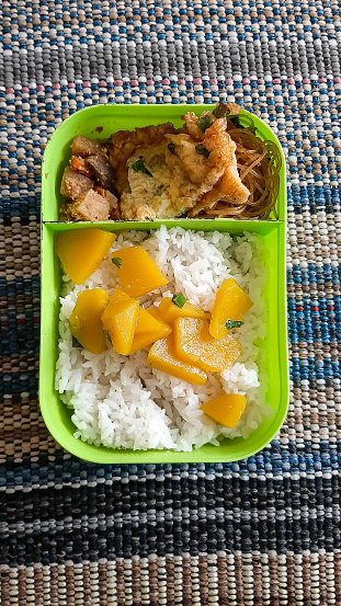 packed rice with side dishes of yellow pumpkin and other supporting vegetables. Rice for school children with a simple menu