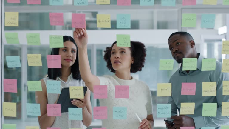 Business people, collaboration and sticky notes on glass board for data analytics, planning ideas and teamwork. Creative team, women and men with digital tablet, brainstorming or SEO for social media