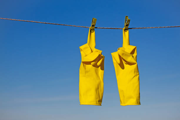istock Yellow Rubber Gloves Drying on a Rope with Middle Finger Up Gesture 1916485535