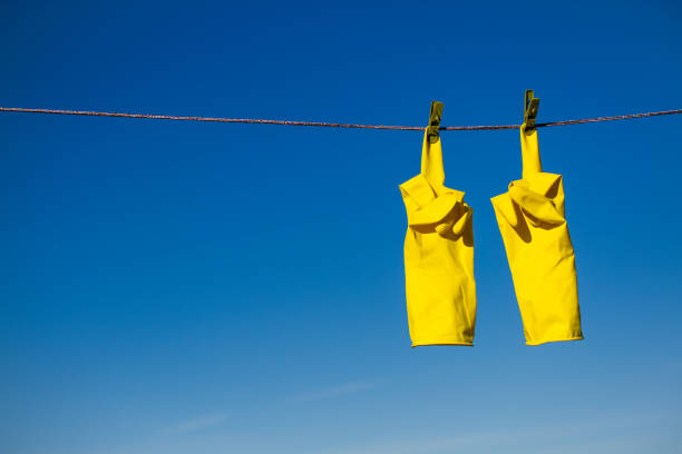 istock Yellow Rubber Gloves Drying on a Rope with Middle Finger Up Gesture 1916486580