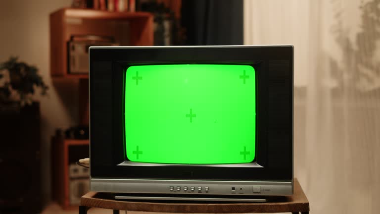 Old television with green chroma key screen at home. Close-up of vintage tv in living room, nostalgia.