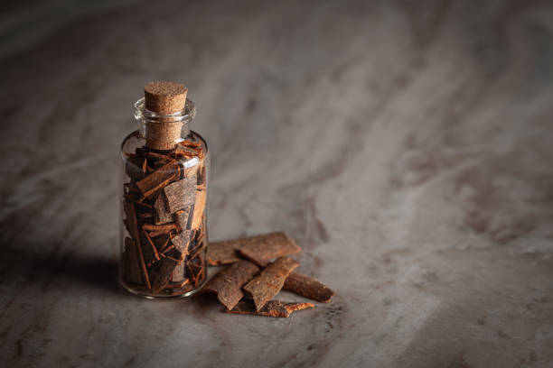A close-up image of pieces of dry galangal root resting on a wooden bedside table. One piece appears partially burnt, symbolising its use in natural, alternative medicine. This detail reinforces the connection to holistic, new age practices.