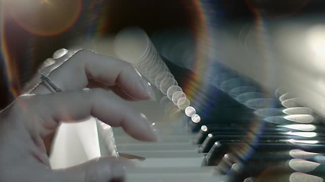 Female hands playing on a synthesizer keyboard (piano) shining in the backlight
