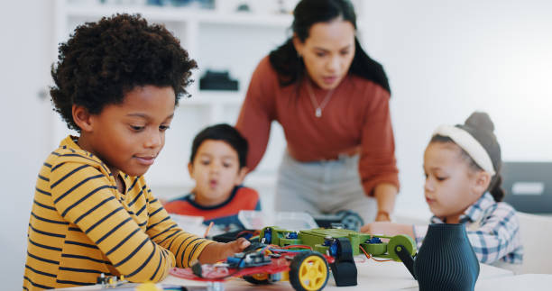 istock Electronics, boy and car robotics in classroom for learning, education or technology with car toys for innovation. School kids, learners and transportation knowledge in science class for research 1916552611