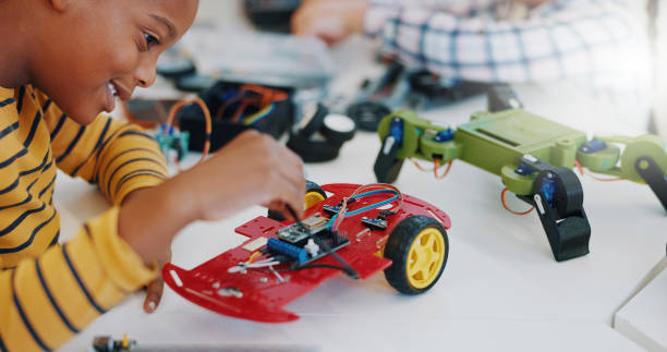istock Robotics, boy and technology in classroom for education or learning electronics with car toys for innovation. School kids, learners and transportation knowledge in science class for research or study 1916552617