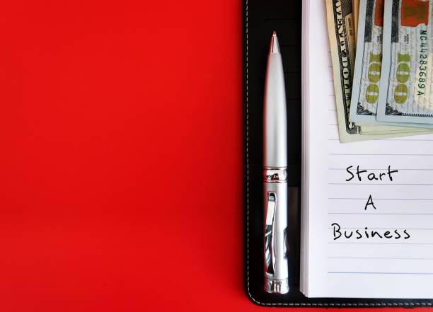 istock On copy space red background, notebook, money and pen with handwritten text START A BUSINESS, concept of new small business startup plan to launch business on their own 1916554196