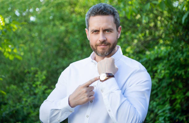 istock Professional guy pointing finger at wristwatch natural background, punctuality 1916561027