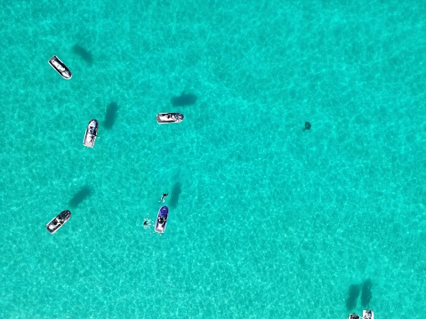 A peaceful scene of a cluster of boats drifting in the tranquil blue sea