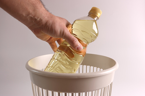 A bottle of expired vegetable oil is thrown into the recycling bin