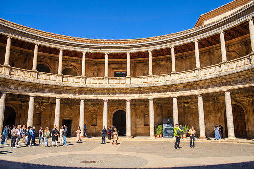 Tourists visiting the Patio of the Palace of Charles V, a Renaissance building whose construction began in 1527 inside the Alhambra of Granada, the monumental complex that is the main landmark of the city.