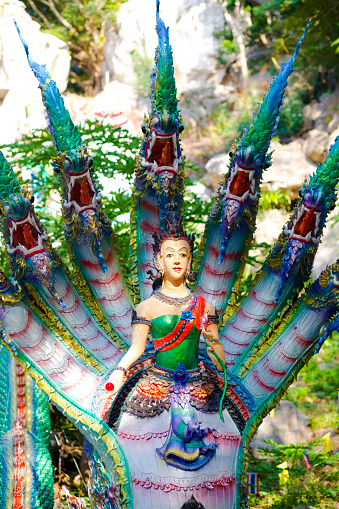 Thai Nakhon snakes with mermaid statue. Statues are at side of steps and blue colored and are on grounds of temple in small village Paranghmee near Noen Maprang in Phitsanulok province. Steps are leading up to buddha statues high up on a rock