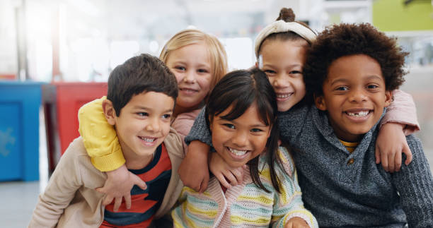 Portrait, groupe et enfants avec le sourire à l’école pour l’éducation, l’apprentissage et la connaissance avec câlin. Étudiant, enfants ou face au bonheur dans la salle de classe pour l’étude, la bourse ou le développement de l’enfance - Photo