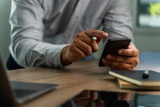 istock businessman holding a smartphone in the office, working online, looking mobile Communication and technology concepts 1916628285